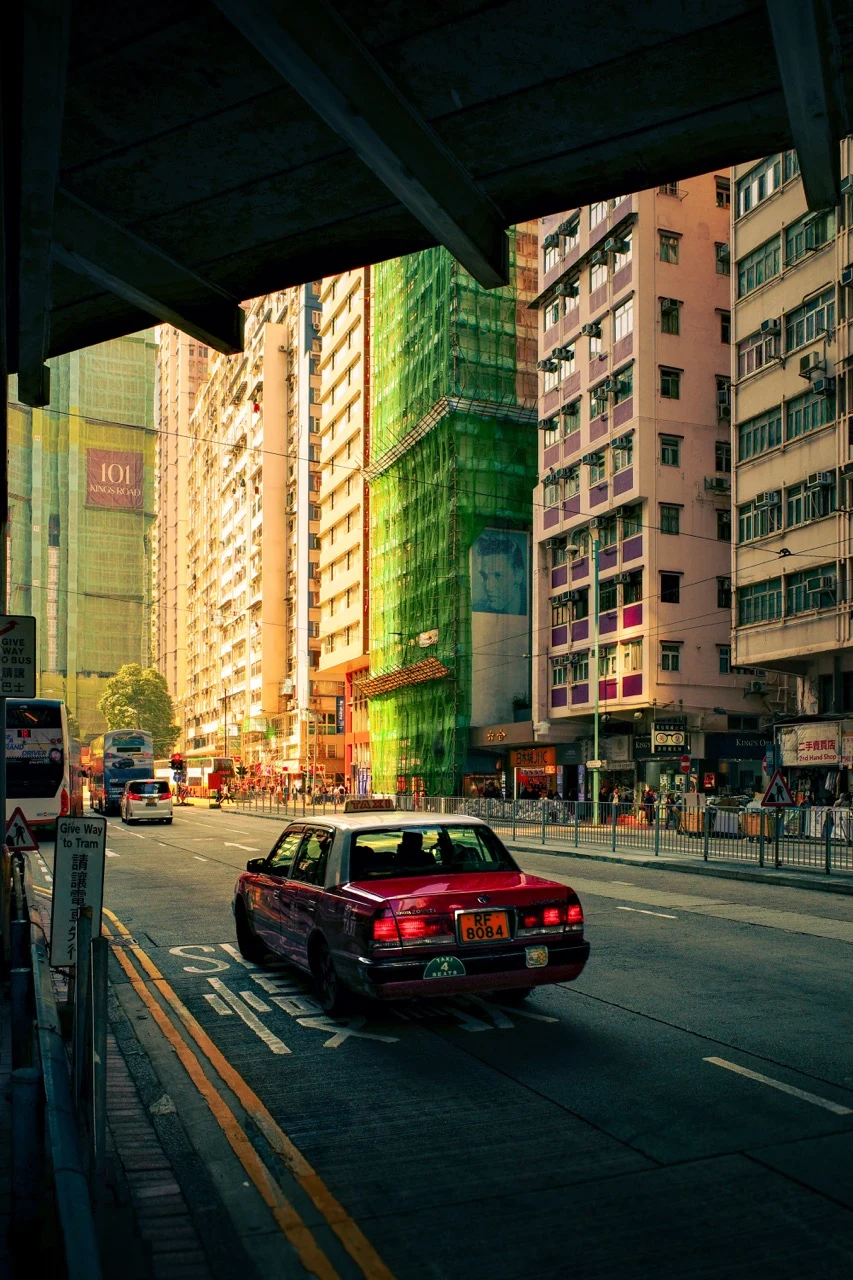 A red taxi passing through a city street